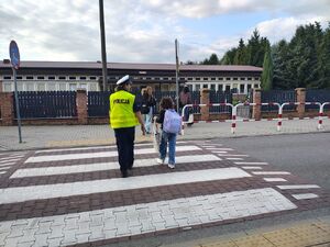 policjanci przeprowadzają dzieci przez pasy.