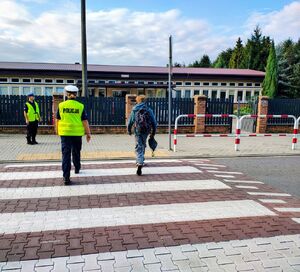 policjanci przeprowadzają dzieci przez pasy.
