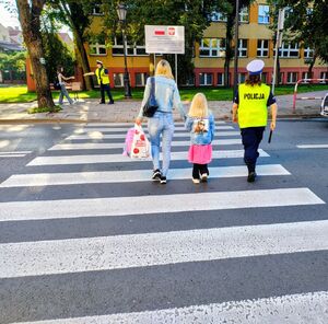 policjanci przeprowadzają dzieci przez pasy.