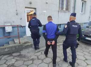 policjanci prowadzą zatrzymanego.