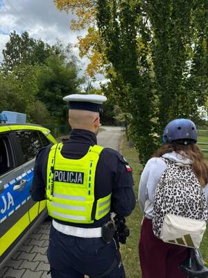 Policjant ruchu drogowego kontroluje rowerzystę.