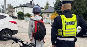 Policjant ruchu drogowego kontroluje rowerzystę.