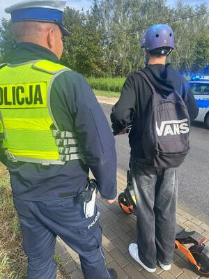 Policjant ruchu drogowego kontroluje małoletniego na hulajnodze elektrycznej.