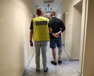 policjant prowadzi zatrzymanego.