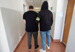 policjant prowadzi zatrzymanego.