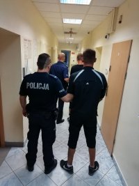 policjant stoi tyłem  a obok niego zatrzymanymi, przed nimi kolejna para policjant zatrzymany